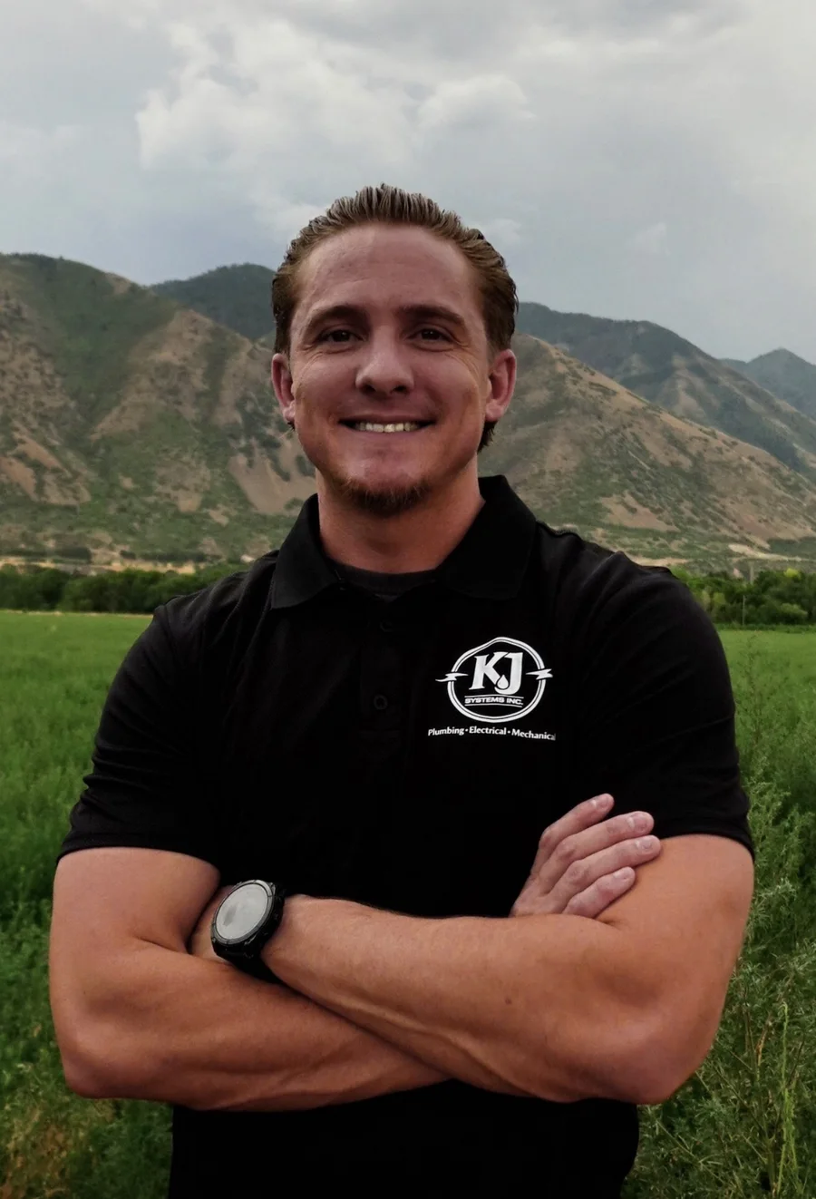 Jace Johnson, Owner of KJSYSTEMS Inc., arms crossed in front of the mountains